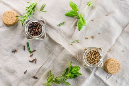 Coriander seeds and dried cloves on the background with some aromatic plants. Species and ingredients for cooking concept. Top View.の写真素材
