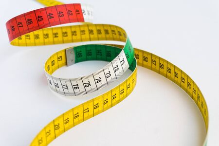 Creative photo of a colorful measuring tape isolated on a white background. Diet and measure...
