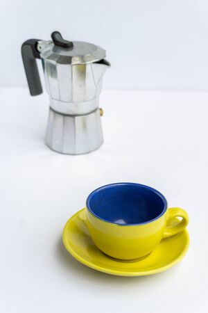 Colorful dirty cup of coffee with a Italian coffee maker machine on the background isolated on white.の写真素材