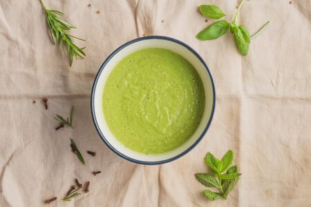 Healthy and vegan green peas cream soup with some aromatic plants on the background. Natural colors. Summer and fresh food concept.の写真素材