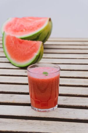 Summer fresh watermelon juice on a wooden table with slices of watermelon on the background. Summer food and drinks concept.の写真素材