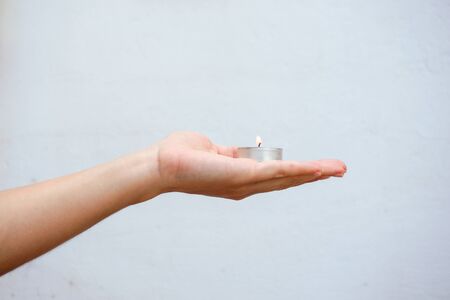 Woman hand holding a burning candle. Close up view.の写真素材