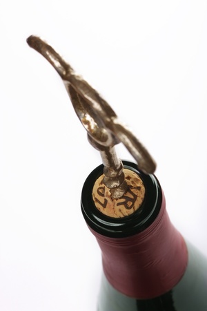 Corkscrew inserted into a wine fuse in a bottle on whiteの写真素材