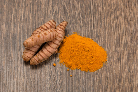 turmeric powder with turmeric root over woodの写真素材