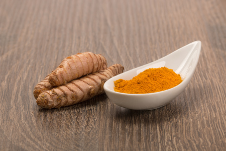 Composition with bowl of turmeric powder on wooden tableの写真素材