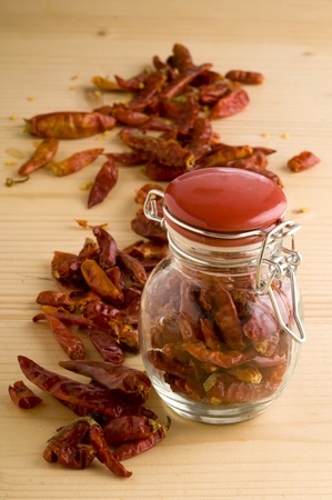dried pepper in a glass pot on a wooden surfaceの写真素材