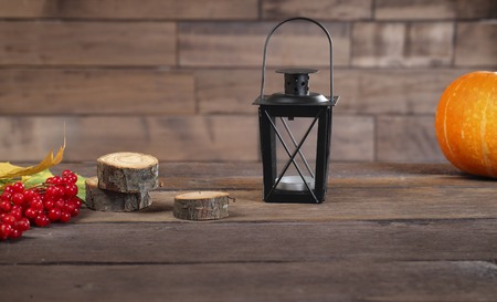 Red viburnum berries, tree stumps, candlestick, pumpkin and leaves on the dark textured wooden boardの写真素材