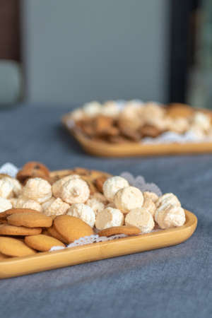 assorted cookies on a wooden plate. vertical photo. in the background is a second plate of cookiesの写真素材