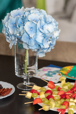 branch of blue hydrangea in a vase near fruit dessertの写真素材
