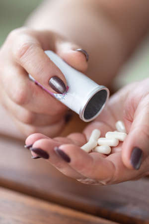 an aged woman poured all the medicines from a jar into her handの写真素材