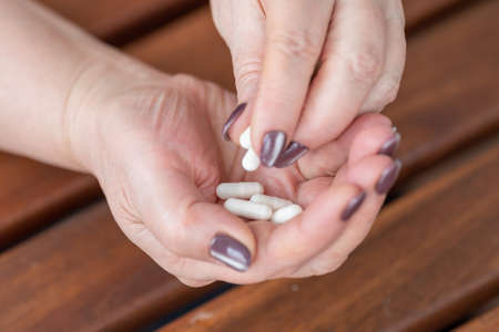 an elderly woman holds a handful of medicine capsules in her hands.の写真素材