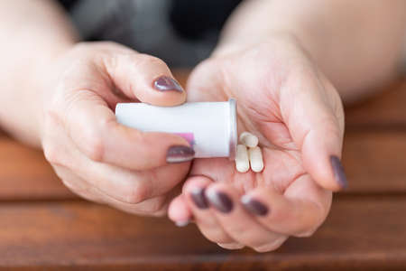 woman pours all the medicines from a jar into her handの写真素材