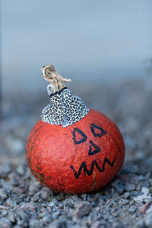 small orange pumpkin decorated for Halloween. a face was drawn and a cap was madeの写真素材