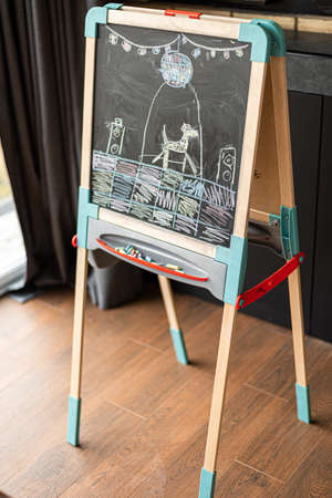 Drawing of a dog on a checkered floor of a seven-year-old girl on a blackboard indoors.の写真素材