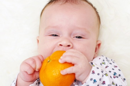 The baby bites tangerine  3,5 months  の写真素材