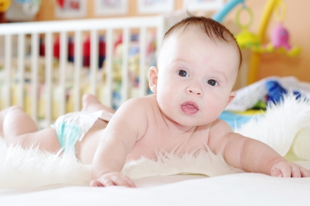 The baby lying on a fur plaid against a white bed  4,5 months  の写真素材