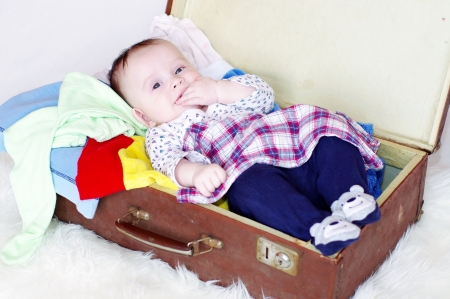 The happy baby lying in an old suitcase with clothesの写真素材
