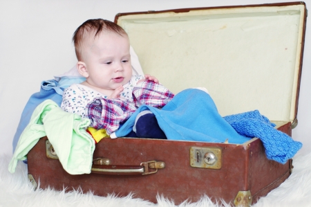 The baby sits in an old suitcaseの写真素材
