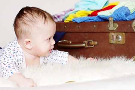 The five-months baby looks at an old suitcase の写真素材