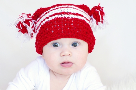 Portrait of the surprised baby in red knitted hat の写真素材