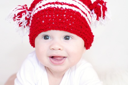 Portrait of the smiling baby in a red knitted hatの写真素材