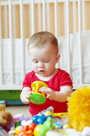 baby plays rattle against white bed の写真素材