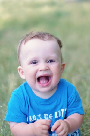 portrait of  laughing baby boy age of 9 months outdoorsの写真素材