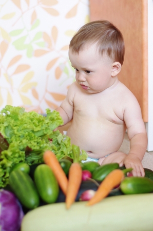 baby with vegetables on kitchenの写真素材