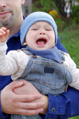 crying baby on fathers hands outdoorsの写真素材