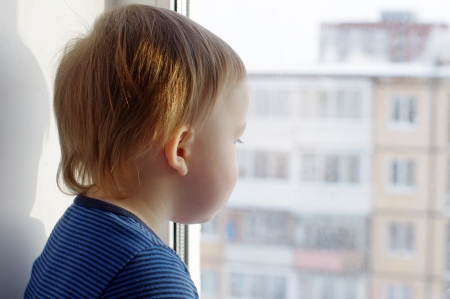 lovely baby age of 1 year looks out of window の写真素材