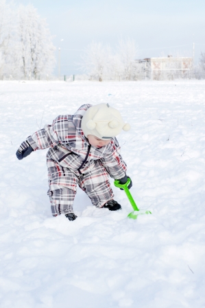 lovely 1 year baby with shovel in winter outdoorsの写真素材