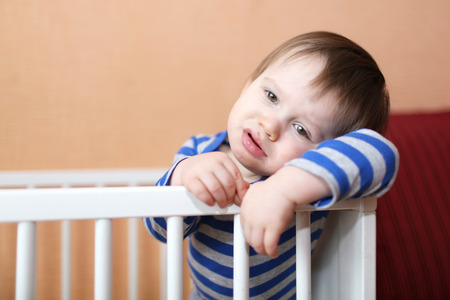 sad 1 year baby in white bed at homeの写真素材