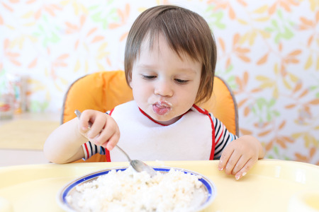happy baby boy eating quark by himselfの写真素材