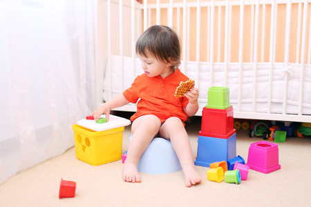 lovely baby boy plays toys sitting on pottyの写真素材