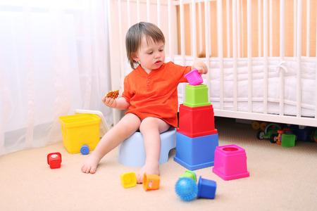 lovely baby boy plays toys sitting on pottyの写真素材