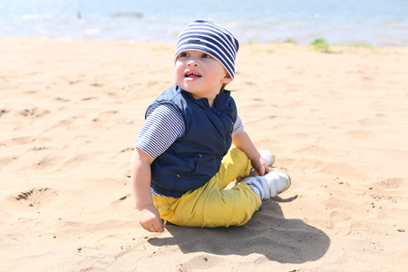 baby boy sitting on shore of the lake 