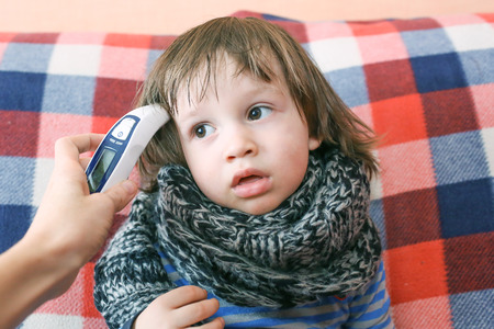 Mother takes temperature for her child with infrared thermometerの写真素材
