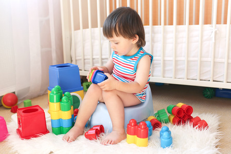 lovely baby boy (22 months) plays toys sitting on pottyの写真素材