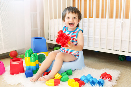 lovely baby boy plays toys sitting on pottyの写真素材