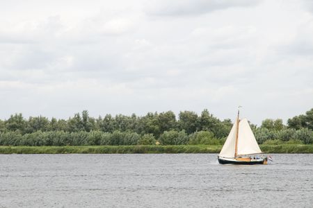 old sailingboat on the river with rain cloudsの写真素材