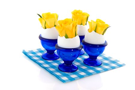 Yellow roses in blue egg cups and eggs