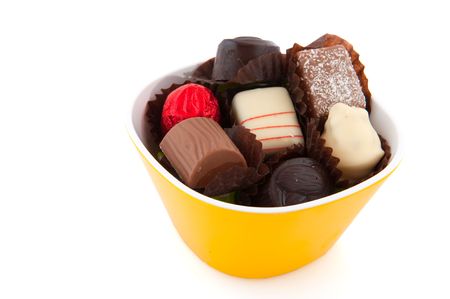 Belgian chocolate candy bonbons in yellow modern bowl isolated over whiteの写真素材