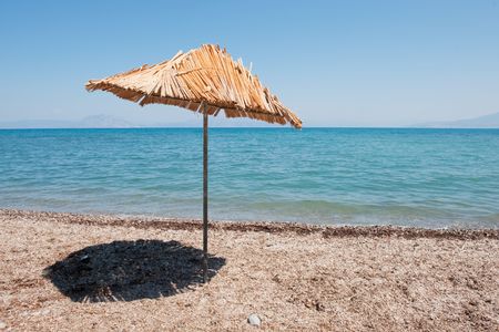 Beach with straw parasol at the coastの写真素材