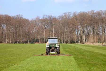 Mowing the young grass by a tractorの写真素材