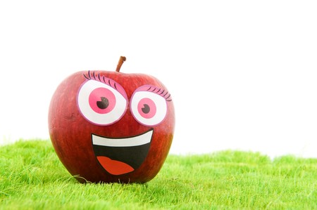 Funny apple with a face in the grassの写真素材