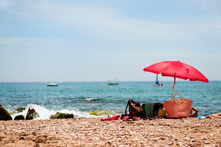 Beach with parasol and bags in the sandの写真素材