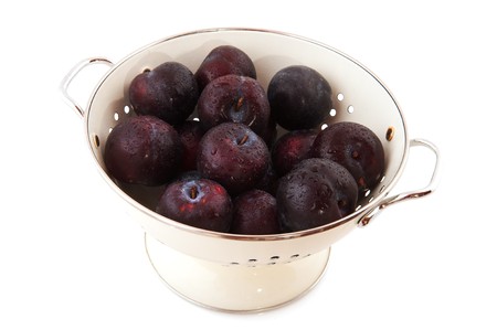 White colander filled with fresh red or blue plumsの写真素材