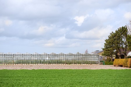 Glass greenhouse exterior in landcape with grassの写真素材