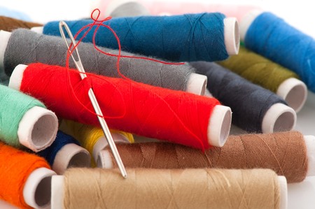 colorful sewing threads on spools with needle