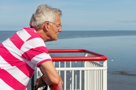 Elderly man is looking over the railing on the cruise boatの写真素材